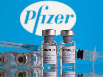 Frascos rotulados como de vacina contra Covid-19 em frente ao logo da Pfizer