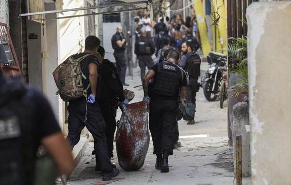 Policiais carregam corpo durante operação na favela do Jacarezinho