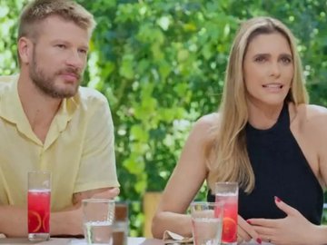 Rodrigo Hilbert com camisa amarela e Fernanda Lima de roupa preta, sentados à mesa em programa de TV