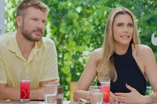 Rodrigo Hilbert com camisa amarela e Fernanda Lima de roupa preta, sentados à mesa em programa de TV